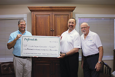 Manager of Operations Mike Dillon, left, and Board member Tom Rice, accepts check from Christopher Kittleson, center.